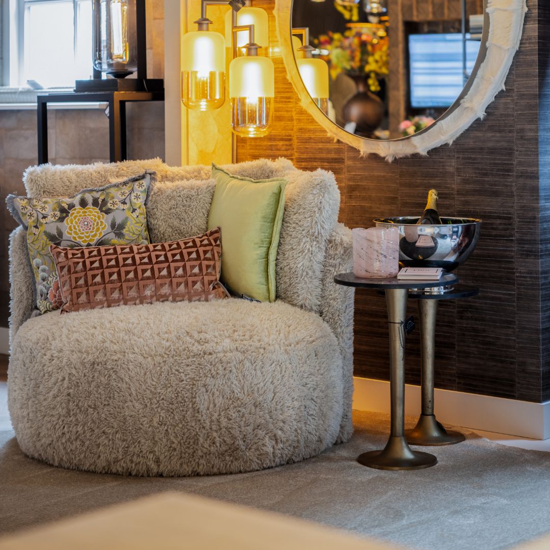 Een witte teddy fauteuil met verschillende gekleurde kussens