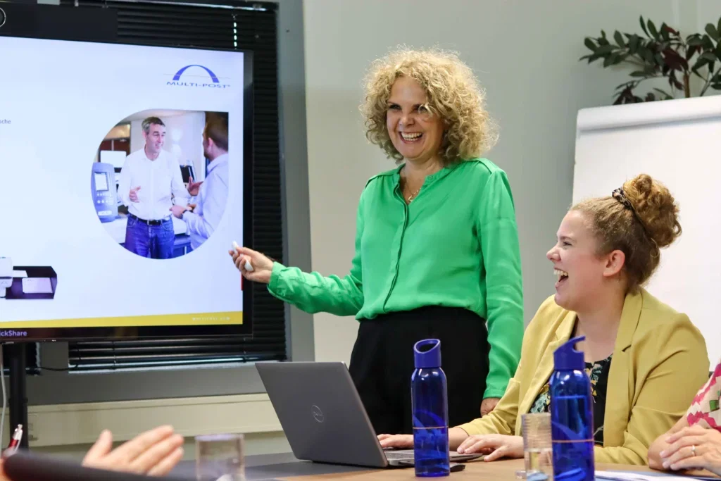 Medewerkers lachend tijdens een presentatie Medewerkers lachend tijdens een presentatie