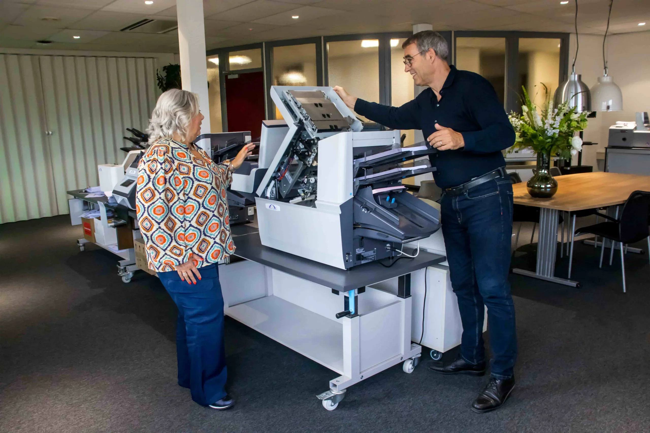 Twee personen bij een opengeklapte machine