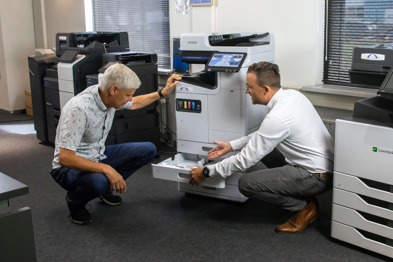 Twee personen gehurkt bij een printer Twee personen gehurkt bij een printer